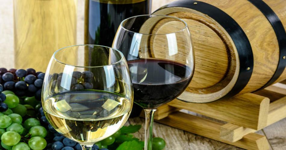 rode en witte wijn in een glas naast een houten wijnvat
